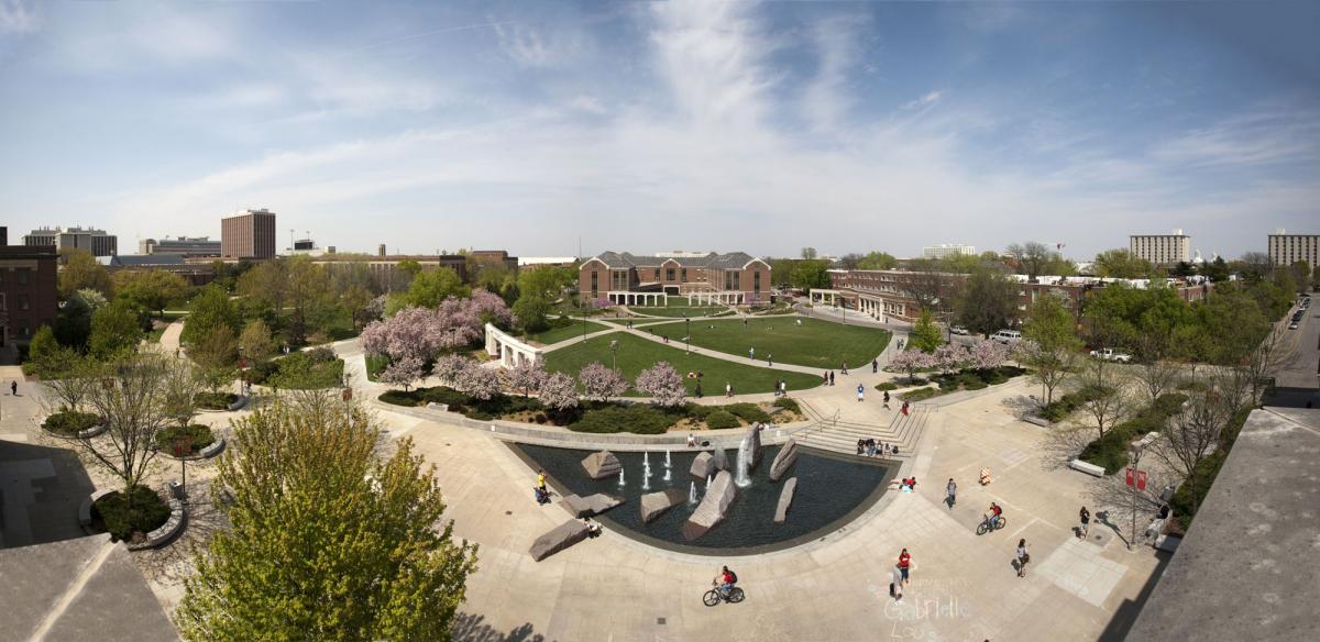 panorama of campus from the Nebraska Union showcasing students, the fountain, green space, and campus buildings
